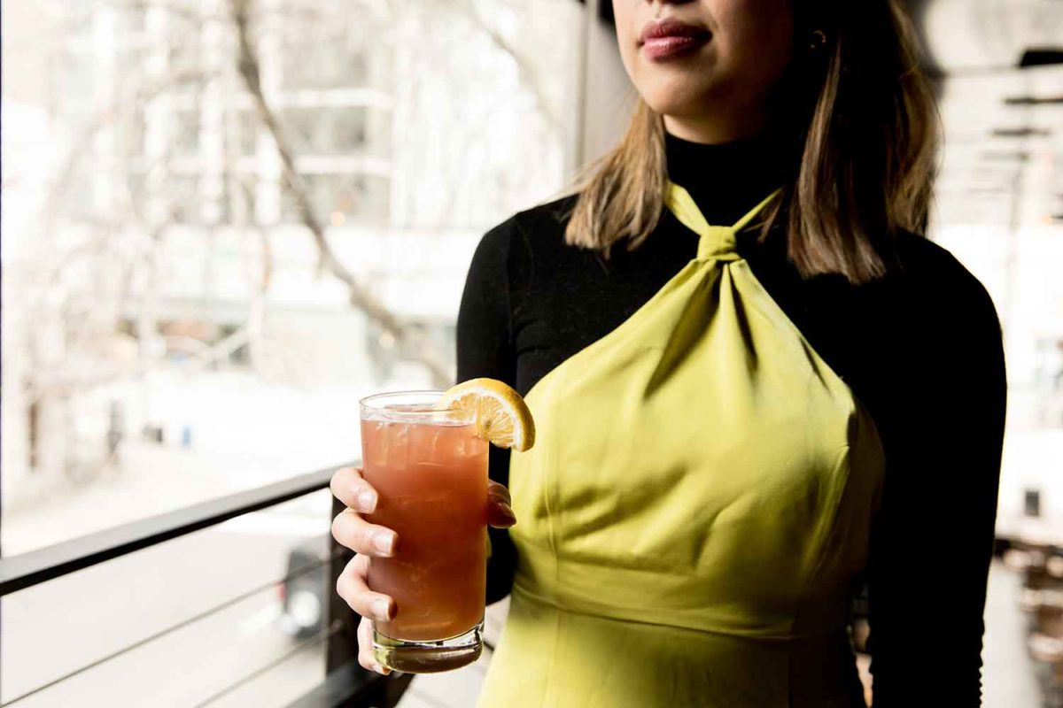 woman holding cocktail by a window