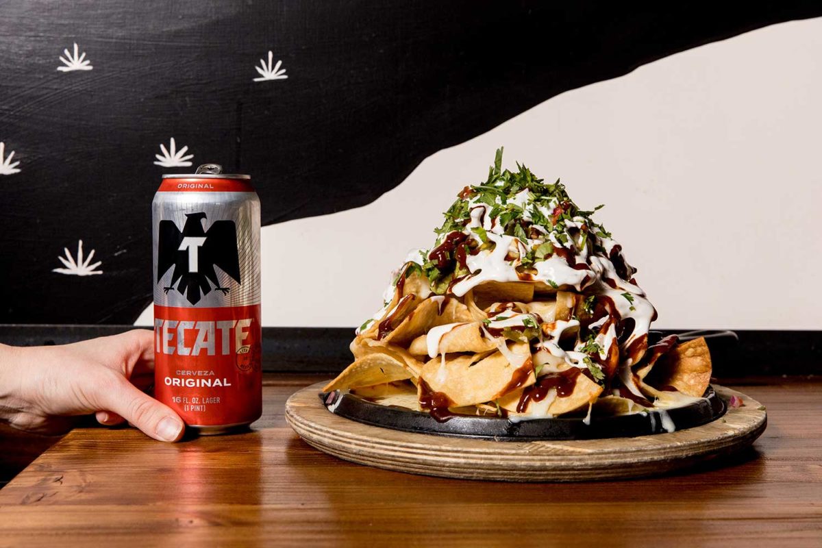 can of tecate alongside giant pile of nachos