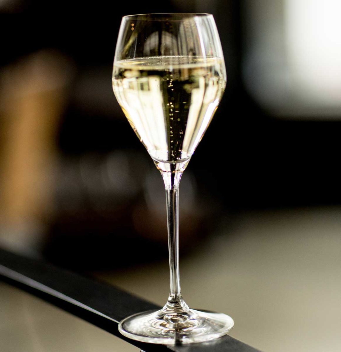 glass of bubbly balanced on top of bar railing