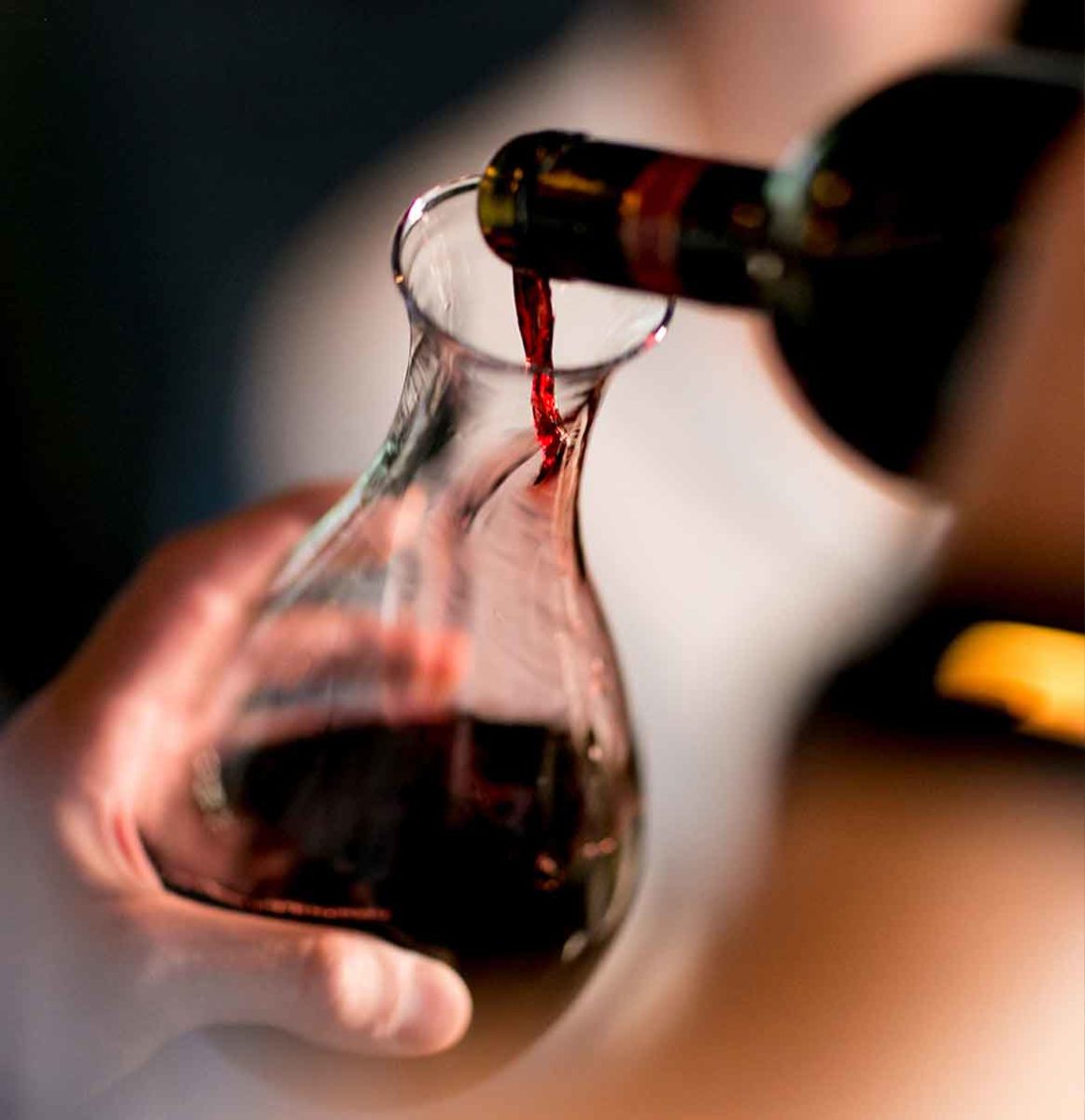 server pouring a bottle of red wine into decanter.